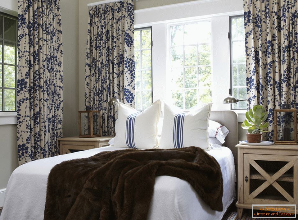 Сині квіти на шторах і смуги на подушках гармонійно поєднуються в інтер'єрі спальні