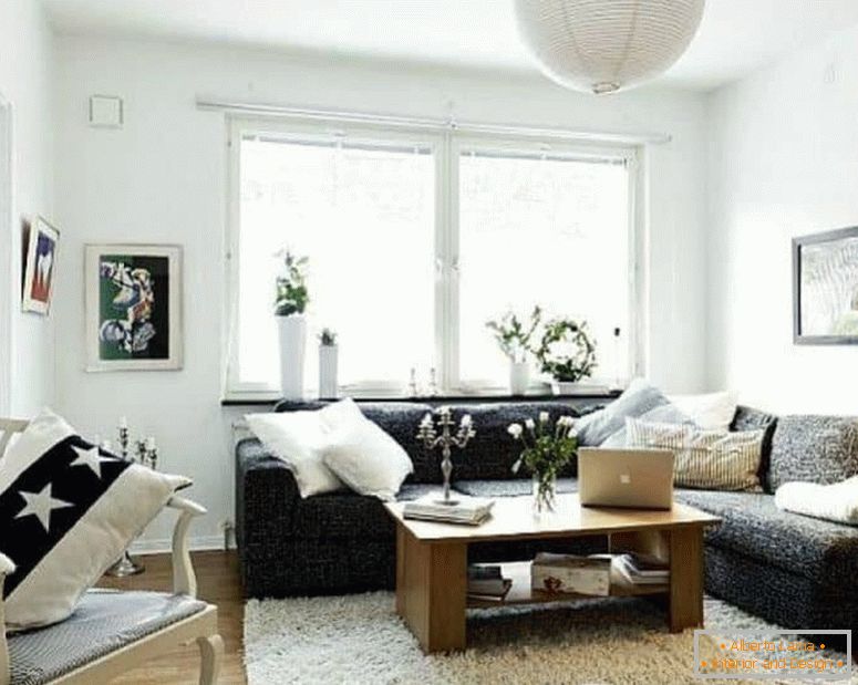 Маленька вітальня в білому з темним кутовим диваном і вікном