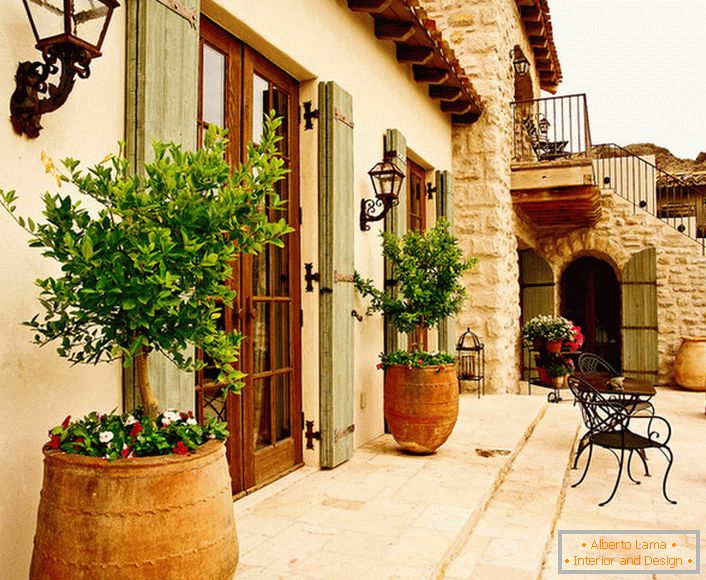 Внутрішній дворик в середземноморському стилі прикрашають горщики з живими рослинами. Привабливий дизайн, меблі з витіюватими спинками, керамічні горщики створюють затишну, розслаблюючу атмосферу.