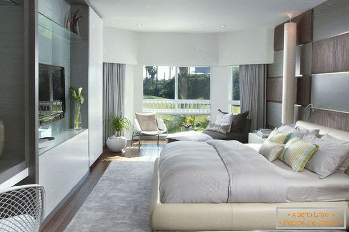 М'яка, об'ємна ліжко в спальні в модерн стилі. Меблі з глянцевою поверхнею вигідно вписується в загальну композицію інтер'єру.