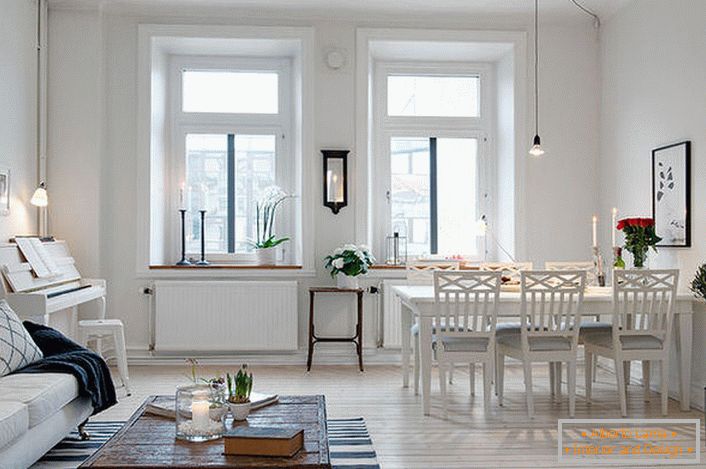 Стильна вітальня розділена на зону відпочинку і обідню зону. Відповідно до скандинавським стилем стіни кімнати оформлені в білому кольорі.
