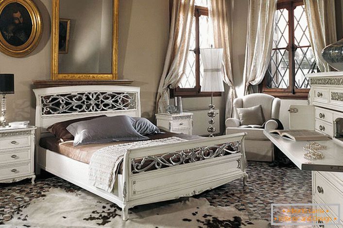 Дотримана основна вимога барочного стилю. У просторій спальній кімнаті з високими стелями біла дерев'яні меблі контрастно виглядає на тлі темних віконних рам.