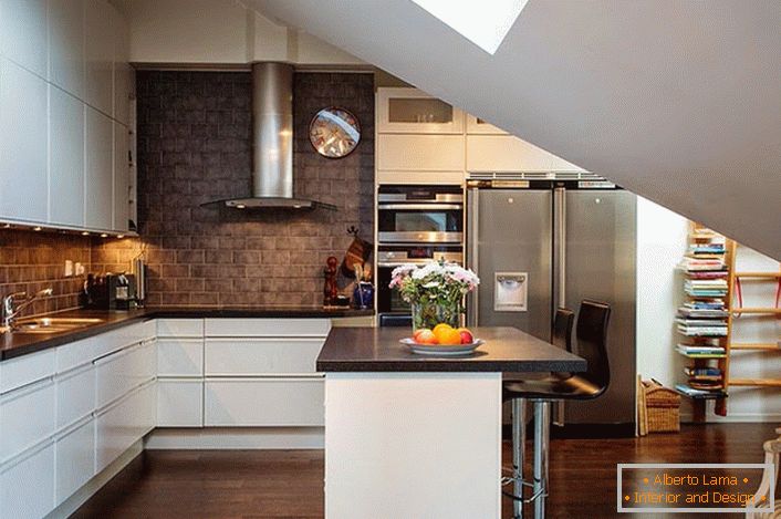 Кухня на мансардному поверсі оформлена в скандинавському стилі. Білий кухонний гарнітур вигідно виглядає на тлі обробки стін з темного цегли. 