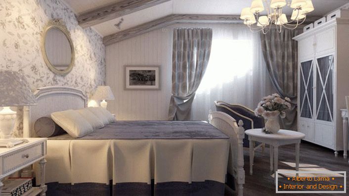Спальня в стилі кантрі виконана в приглушених блакитних тонах. Стіна біля ліжка обклеєна шпалерами з квітковим малюнком.