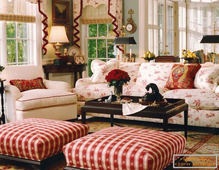 Проста, скромна і затишна вітальня в англійському стилі в невеликому заміському будинку. Акценти червоного роблять обстановку в кімнаті невимушеній і веселою.