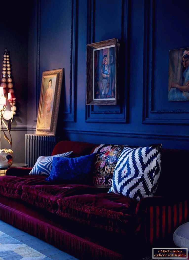 Бордовий диван на тлі темно-синіх стін