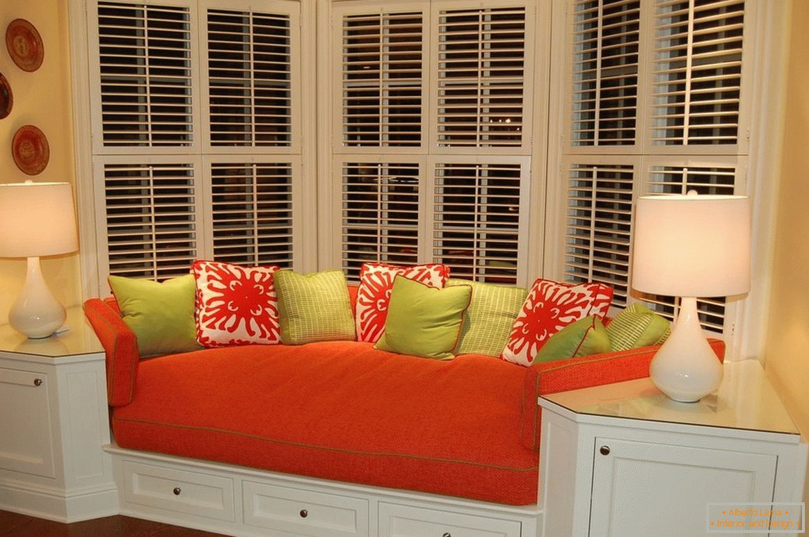 Червоний диван з кольоровими подушками