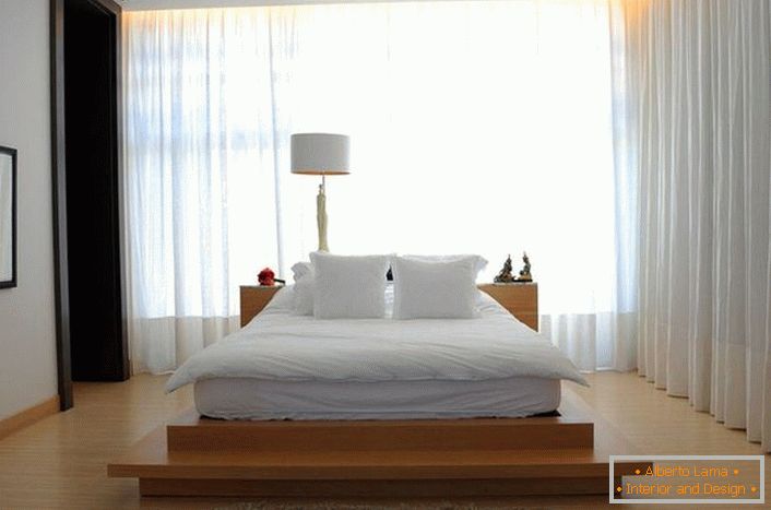Ліжко нагадує велику м'яку перину, яка розташувалася на високому подіумі з дерева. Фіранки з м'якою, напівпрозорої, летючої тканини роблять атмосферу в кімнаті романтичною і розслаблюючій. 