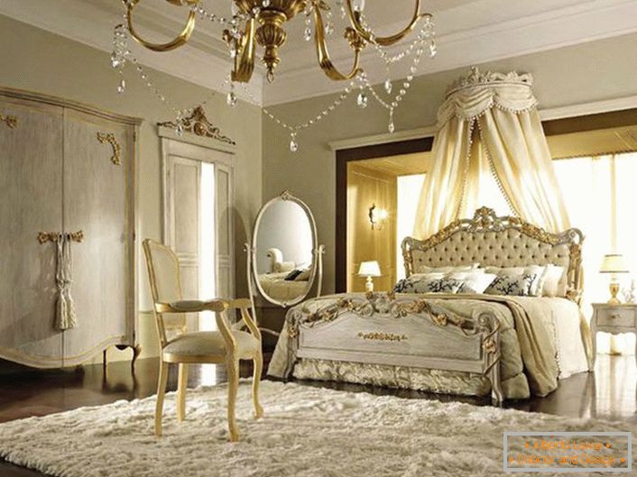 Балдахін над ліжком прибраний за спинку в головах. Ніжно-бежеві відтінки вдало гармоніюють з золотими елементами декору.