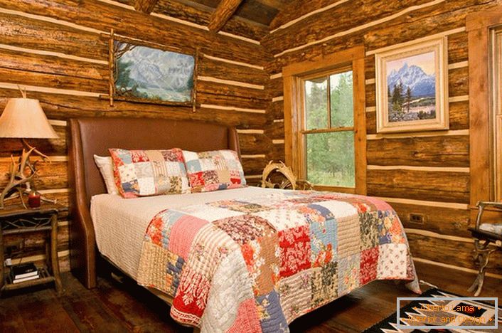 Спальня в сільському стилі в мисливському будиночку. Примітно оформлення стін за допомогою зрубу дерева. 