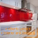 Білі меблі і червоний фартух в інтер'єрі кухні