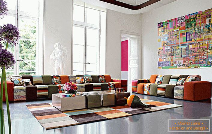 Барвиста гостьова кімната в стилі авангард у великому будинку італійської сім'ї. Дизайнерська ідея грамотно поєднує в собі килимове покриття і меблі приблизно однаковою колірної гами.