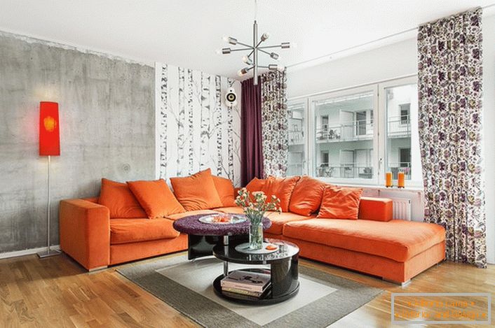 Скандинавському стилю притаманне використання теплих відтінків в оформленні інтер'єру. М'який диван оранжевого кольору органічно виглядає на тлі стін холодно-сірого відтінку.