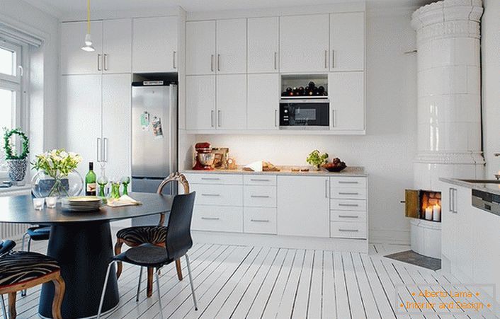 Кахельний камін, оброблений білою керамічною плиткою, органічно вписується в інтер'єр кухні в скандинавському стилі.