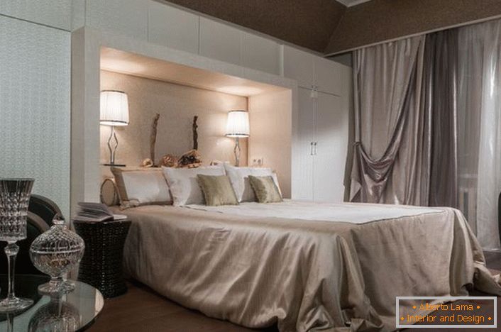 Шляхетний інтер'єр спальні в арт-деко стилі. Увага притягують функціональні шафи білого кольору. Завдяки їм кімната стає досить просторою і світлою.