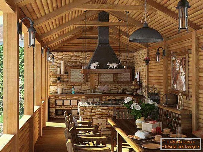 Невелика кухня з мангалом на веранді заміського будинку. Про стилі кантрі свідчить, в першу чергу, обробка стін і стелі дерев'яним зрубом.