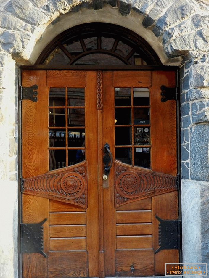 Двері в стилі модерн прикрашають парадний вхід заміського котеджу з фасадом з натурального каменю. 