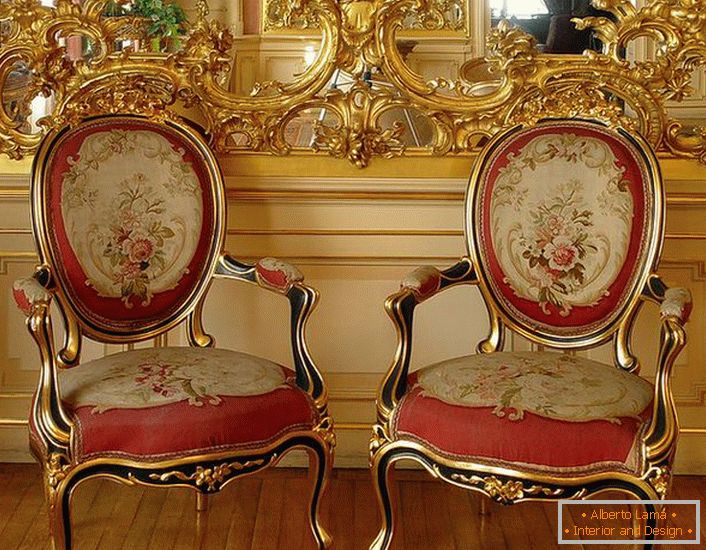Ажурна ліпнина золотого кольору на дзеркалі і стільці з червоною м'якою оббивкою - яскраві представники стилю бароко.