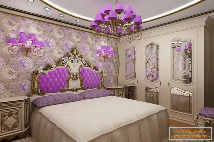 Елегантна спальня барокко з цікавим акцентом на освітленні. Люстра і приліжкові світильники з однаковими фіолетовими плафонами гармонійно поєднуються з оббивкою спинки біля ліжка.