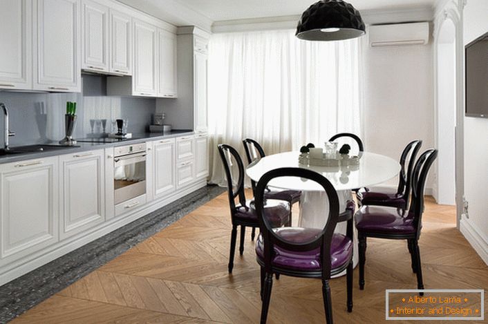 Білосніжний кухонний інтер'єр з акцентами темно-сірого кольору в стилі еклектика. Цікаві стільці з прозорими спинками і фіолетовою м'якою оббивкою.